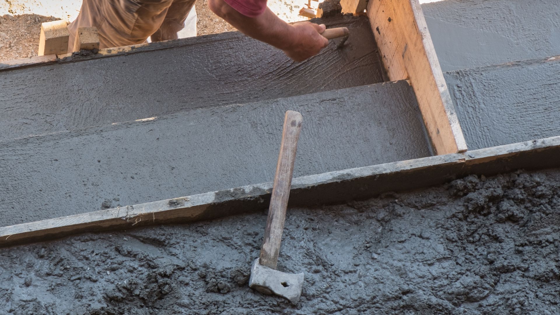 A man laying concrete on top of a building